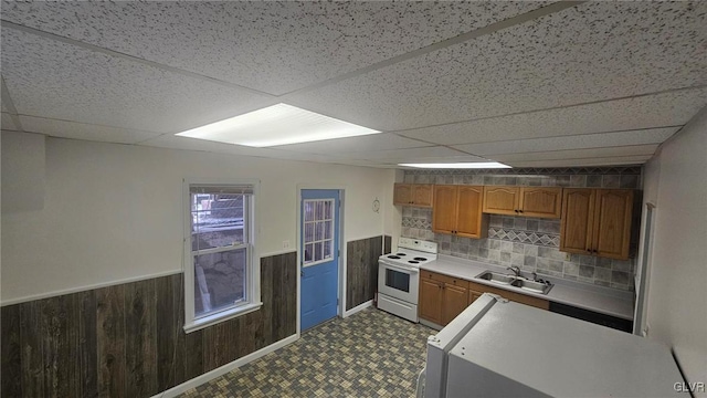 kitchen featuring sink, white electric range oven, a drop ceiling, and wooden walls