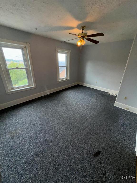 carpeted empty room with ceiling fan and a textured ceiling