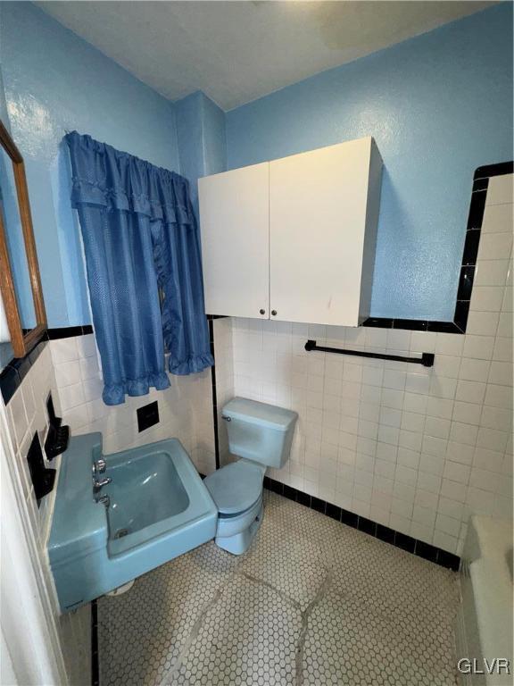 bathroom with sink, toilet, tile patterned flooring, and tile walls