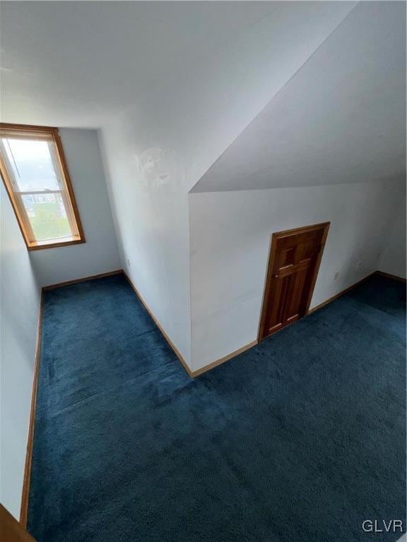 bonus room with lofted ceiling and dark colored carpet