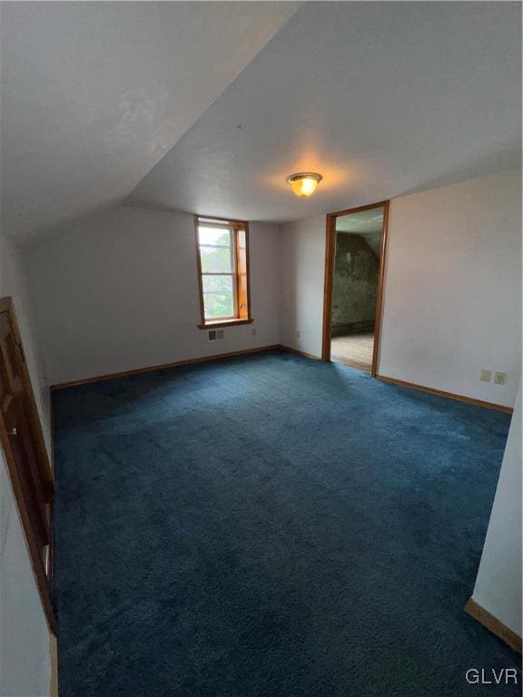 additional living space featuring lofted ceiling and dark colored carpet