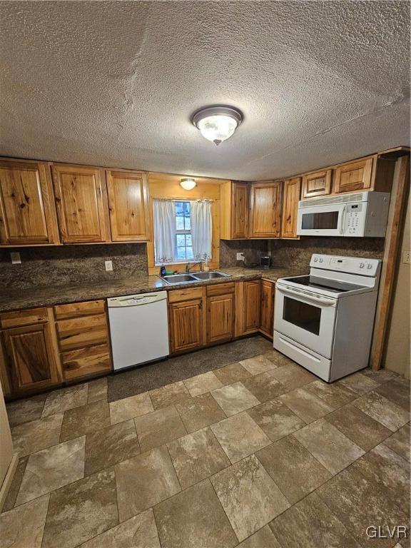 kitchen featuring tasteful backsplash, white appliances, sink, and a textured ceiling