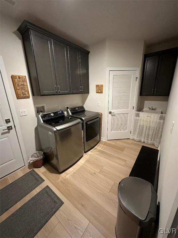 laundry room with cabinets, light hardwood / wood-style floors, and washer and dryer