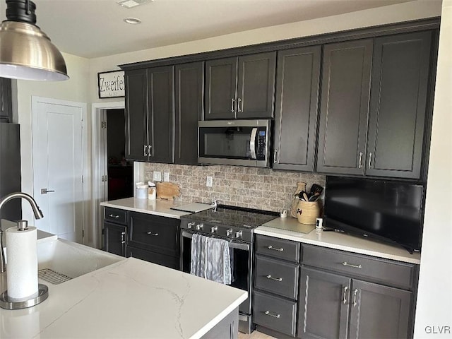 kitchen featuring appliances with stainless steel finishes, light stone countertops, sink, and backsplash