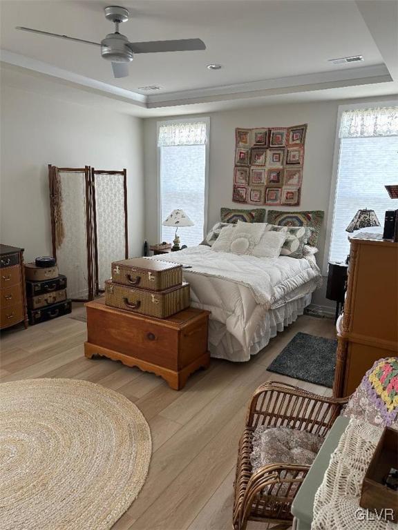 bedroom featuring a tray ceiling, ceiling fan, and light hardwood / wood-style flooring