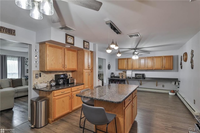 kitchen featuring decorative light fixtures, a breakfast bar area, dark hardwood / wood-style floors, and ceiling fan