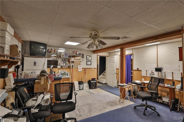 office area with wooden walls, carpet flooring, and a drop ceiling