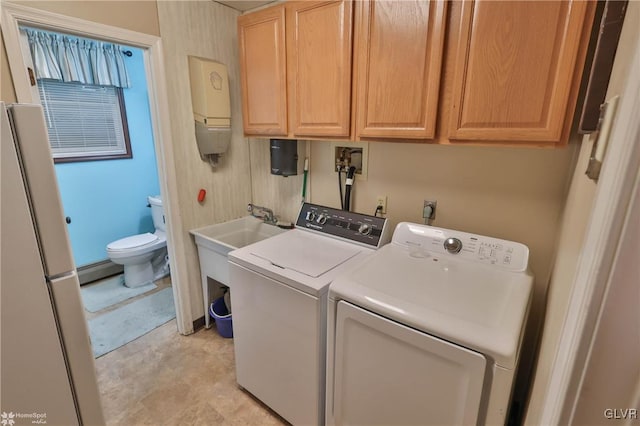 laundry area featuring water heater, a baseboard radiator, washing machine and dryer, and cabinets