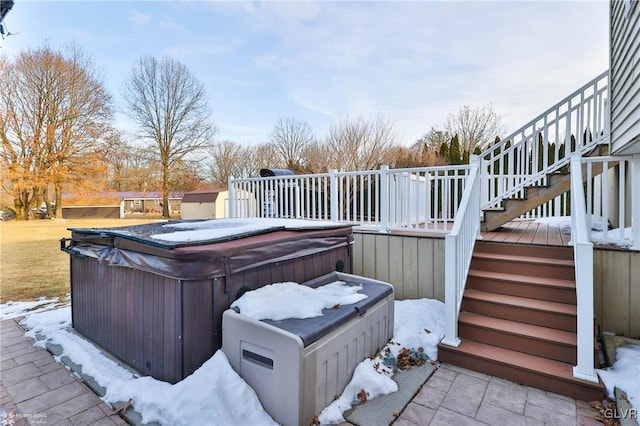 snow covered patio with a wooden deck and a hot tub