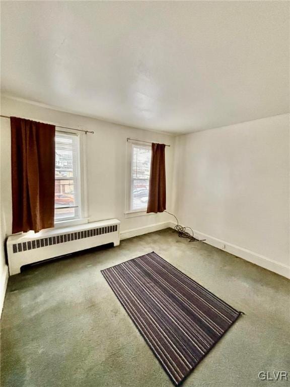 carpeted spare room with a wealth of natural light and radiator heating unit