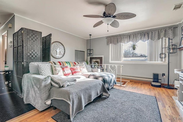 bedroom with hardwood / wood-style floors, crown molding, ceiling fan, and baseboard heating