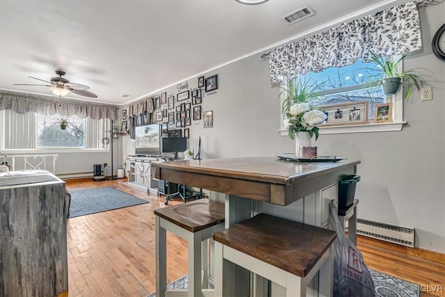 dining room featuring ceiling fan, hardwood / wood-style floors, and a baseboard heating unit