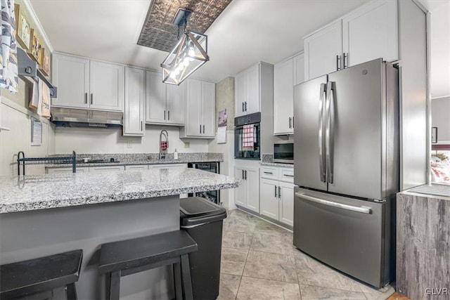 kitchen featuring a breakfast bar, light stone counters, black appliances, white cabinets, and decorative light fixtures