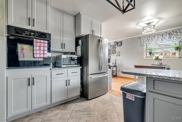 kitchen with gray cabinets, appliances with stainless steel finishes, and light stone counters