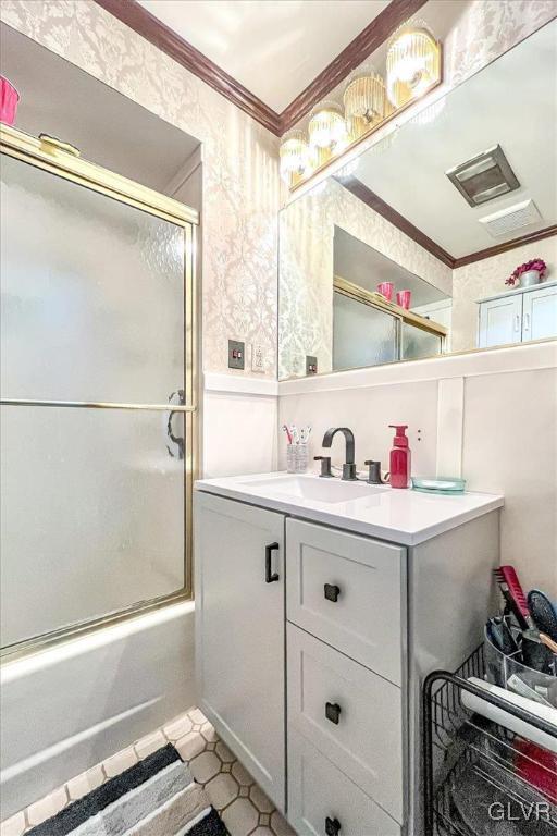 bathroom with vanity, crown molding, and combined bath / shower with glass door