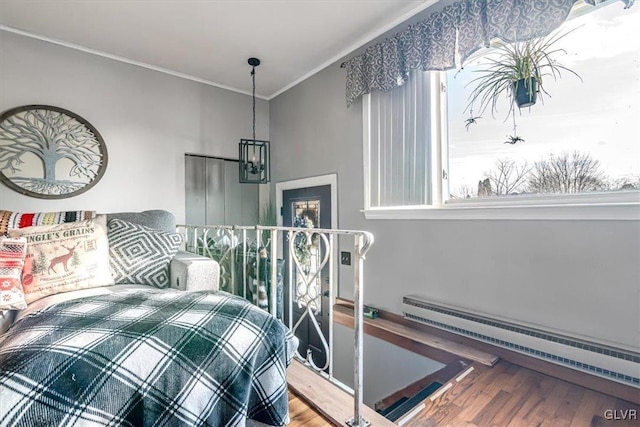 bedroom featuring a baseboard radiator, wood-type flooring, and ornamental molding