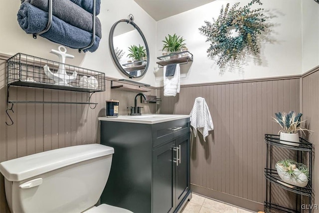 bathroom with tile patterned flooring, vanity, wood walls, and toilet