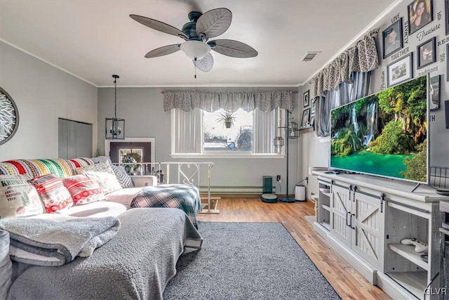 living room with ornamental molding, ceiling fan, and light hardwood / wood-style floors