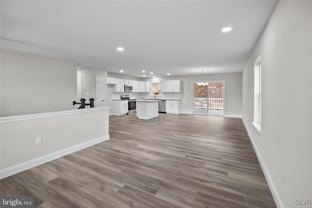 unfurnished living room with an inviting chandelier and hardwood / wood-style flooring