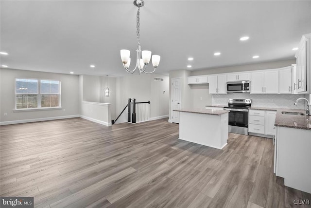 kitchen featuring pendant lighting, sink, white cabinetry, stainless steel appliances, and a center island