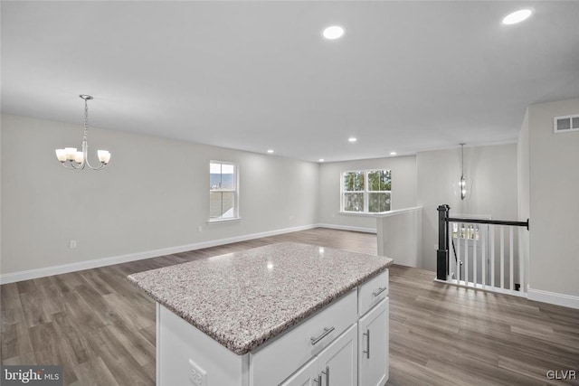 kitchen featuring pendant lighting, a healthy amount of sunlight, hardwood / wood-style flooring, and white cabinets