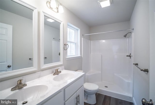 bathroom with wood-type flooring, toilet, vanity, and a shower