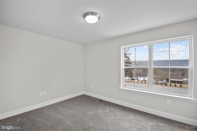 spare room featuring a mountain view and carpet