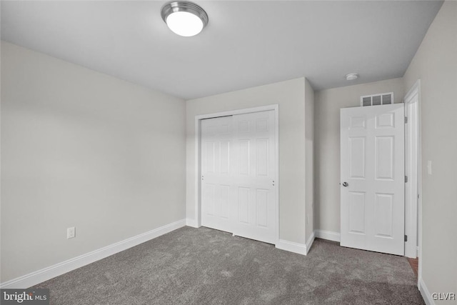 unfurnished bedroom featuring dark carpet and a closet