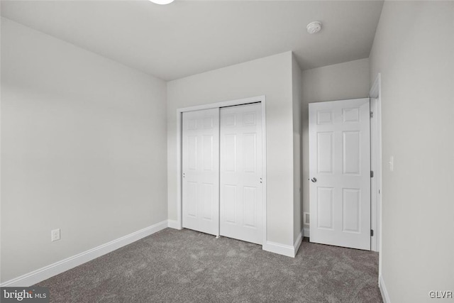 unfurnished bedroom with dark carpet and a closet