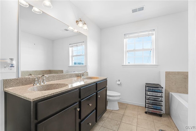 bathroom featuring vanity, a tub, tile patterned floors, and toilet