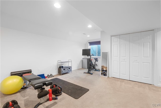 workout area with vaulted ceiling and light carpet