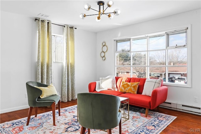 living room with an inviting chandelier, baseboard heating, and hardwood / wood-style flooring