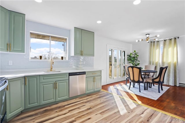 kitchen with tasteful backsplash, dishwasher, sink, green cabinetry, and light wood-type flooring