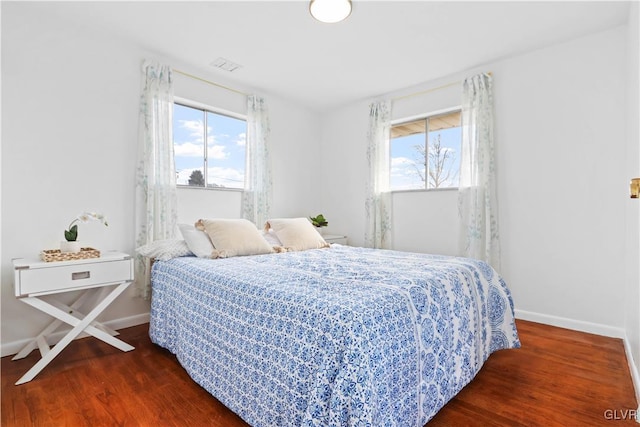 bedroom featuring multiple windows and dark hardwood / wood-style flooring