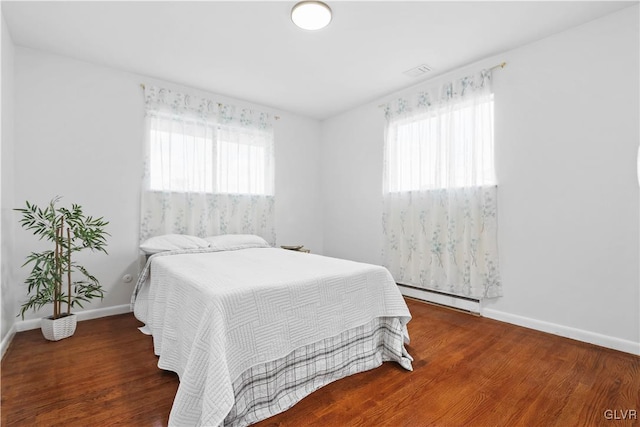 bedroom featuring multiple windows, dark wood-type flooring, and a baseboard radiator