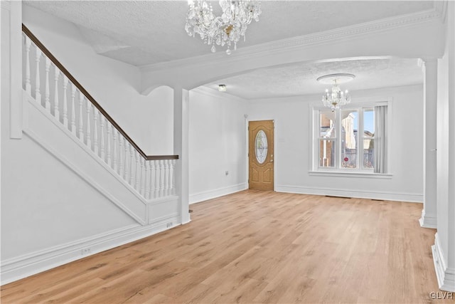 interior space featuring crown molding, a textured ceiling, light hardwood / wood-style flooring, and a chandelier