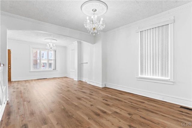 spare room with ornamental molding, hardwood / wood-style floors, a textured ceiling, and a chandelier