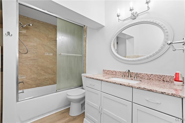 full bathroom with vanity, hardwood / wood-style flooring, toilet, and combined bath / shower with glass door