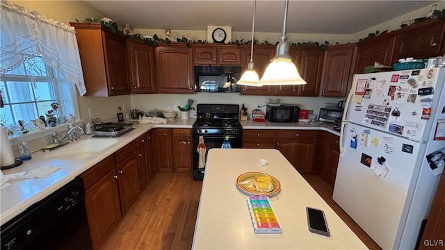 kitchen featuring sink, decorative light fixtures, black appliances, and light hardwood / wood-style floors