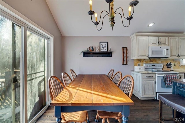 dining room featuring dark wood-type flooring, lofted ceiling, and a chandelier