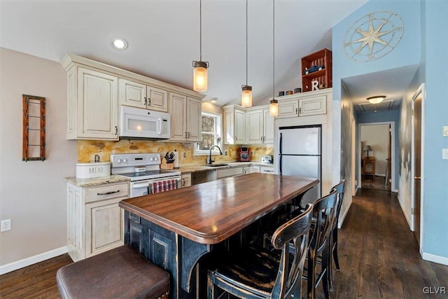 kitchen featuring pendant lighting, sink, white appliances, a breakfast bar area, and a kitchen island