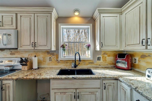 kitchen featuring sink, light stone counters, tasteful backsplash, electric range, and cream cabinets