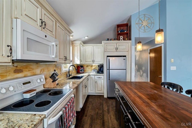 kitchen featuring vaulted ceiling, appliances with stainless steel finishes, decorative light fixtures, butcher block counters, and sink