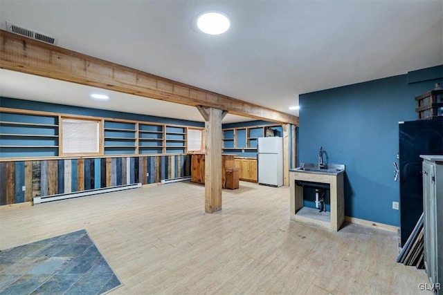 basement with hardwood / wood-style floors, baseboard heating, and white fridge