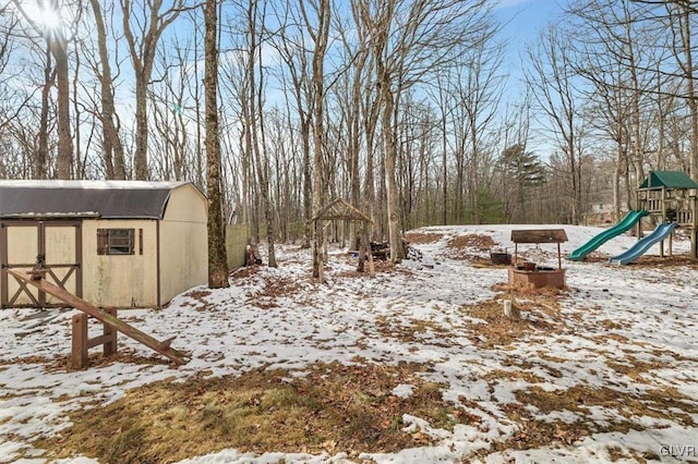 yard layered in snow with a shed and a playground