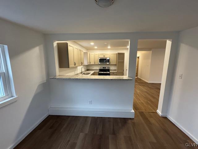 kitchen with dark wood-type flooring, light stone counters, appliances with stainless steel finishes, kitchen peninsula, and white cabinets