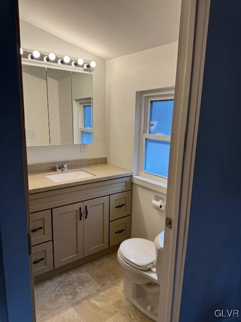 bathroom featuring vanity, lofted ceiling, and toilet