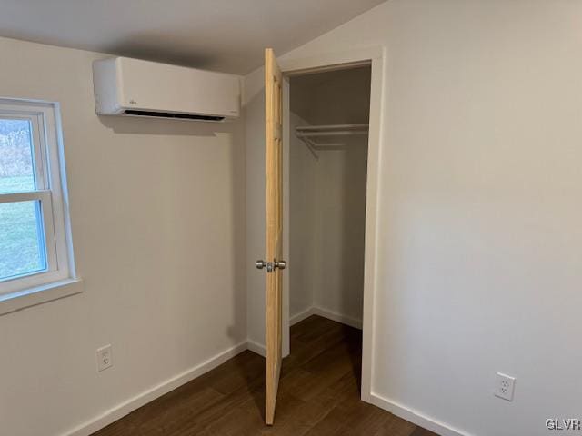 unfurnished bedroom with dark hardwood / wood-style flooring, a closet, and an AC wall unit