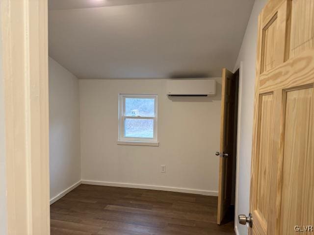 unfurnished room with an AC wall unit and dark wood-type flooring