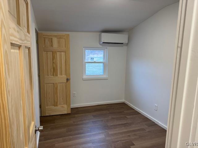 unfurnished bedroom with dark wood-type flooring and an AC wall unit